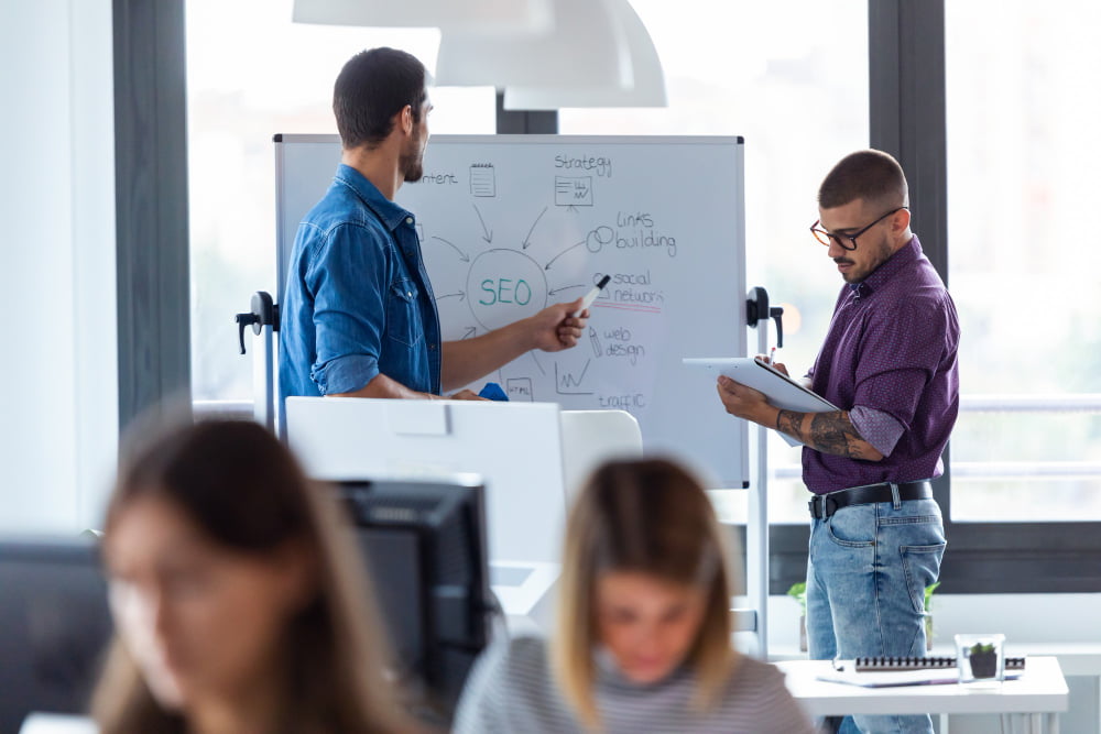 "Grupo de profissionais envolvidos em uma animada discussão sobre as últimas tendências e estratégias de marketing digital, compartilhando conhecimentos e ideias para aprimorar suas habilidades e alcançar resultados ainda melhores."